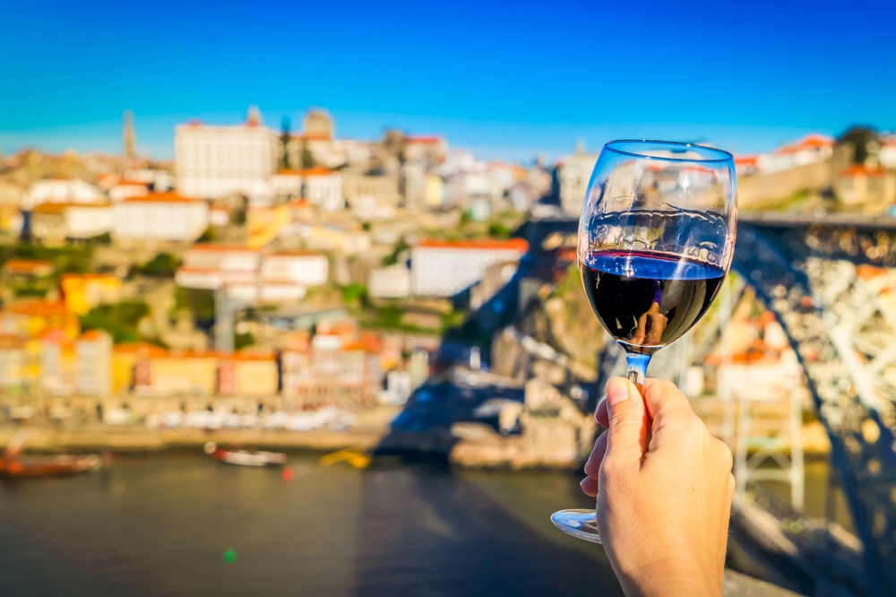 Pohár portského vína s panorámou Porta, riekou Douro a mostom Dom Luís I v pozadí, Portugalsko