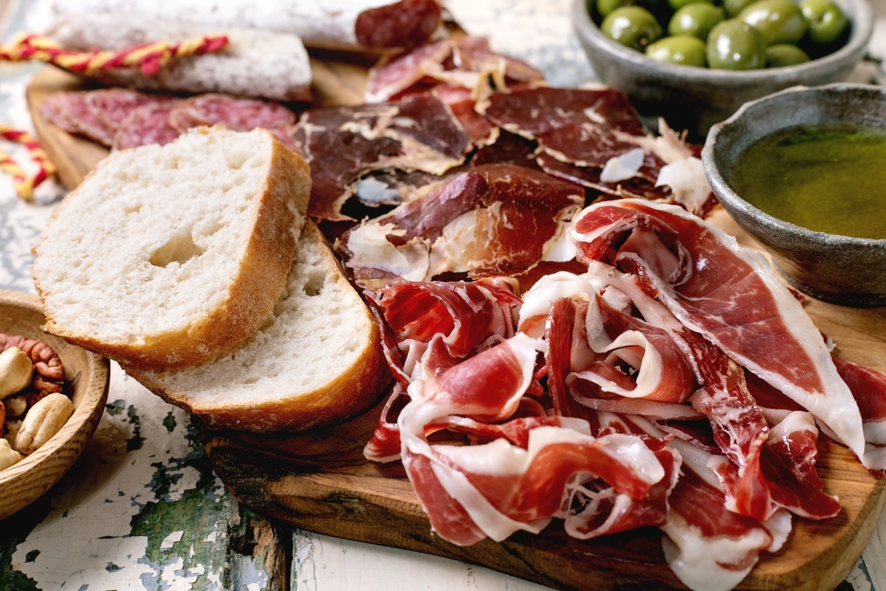 Tradičný španielsky Jamón Ibérico podávaný s chlebom, olivami a olivovým olejom, typická gastronómia Španielska