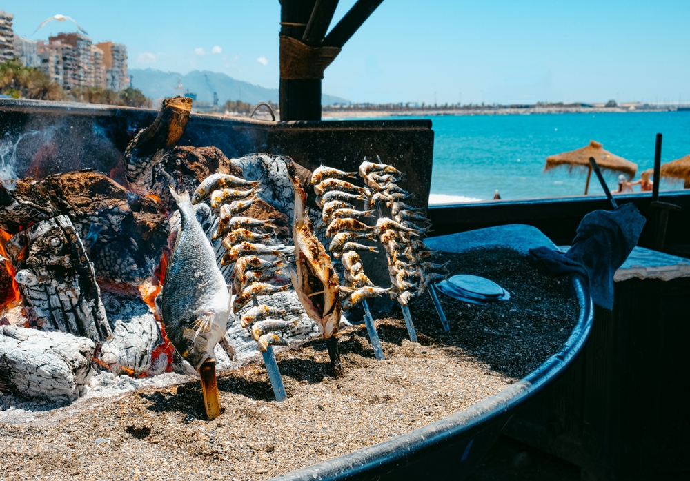 Tradičné espetos de sardinas, sardinky grilované na drevenom ohni pri pláži v Málage, typická gastronómia Andalúzie